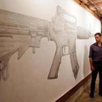 Greg Bokor with his pencil drawing of an AR-15 rifle, which viewers can erase with erasers stamped with the name of a gun victim.