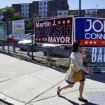 Campaign signs competed for attention on a fence along Dorchester Avenue on Thursday.