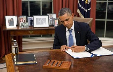 President Obama is seen in a White House photo signing a bill that would provide for payment of Armed Forces  members during a shutdown.
