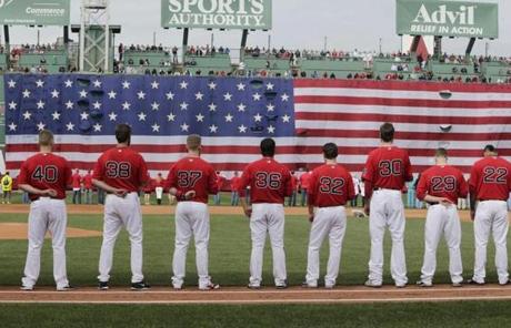 Red Sox players stood before a giant American flag during the national anthem. 
