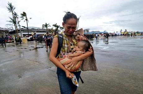 A woman in Leyte, Philippines, weeped as she carried a child to a military aircraft to evacuate the area, which was devastated by Typhoon Haiyan.
