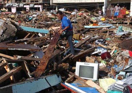 Survivor John Lajara (center) shifted through debris in Tacloban on Saturday. 
