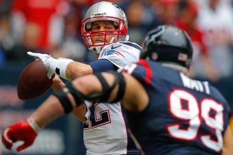 With imposing Texans lineman J.J. Watt bearing down on him, Patriots quarterback Tom Brady (2 touchdowns, 1 interception) gets off a pass during the first quarter.
