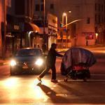 A homeless man pushed a shopping cart full of his belongings across an intersection in the Skid Row area of Los Angeles.
