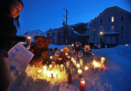 A woman placed a candle during a vigil Wednesday across from the Fitchburg home where Jeremiah Oliver lived.
