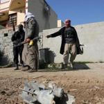Gunmen patrolled near an exploded mortar shell during clashes in Fallujah on Thursday.