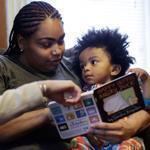 Social worker Stephanie Taveras (left) read a book with Ashley Cox and Cox’s son Jaiden at the family’s Providence home.