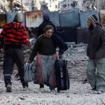 A woman carried her belongings as she walked Monday toward an evacuation point in a besieged area of Homs.