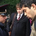 A Sochi police captain detains activist David Khakim while his lawyer Alexander Popkov looks on.