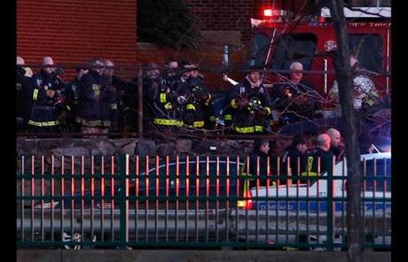 Firefighters lined a railing at the scene to pay tribute to a fallen comrade; other firefighters continued to battle the blaze.
