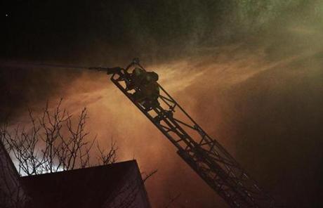 A firefighter sprayed water from the top of a ladder.
