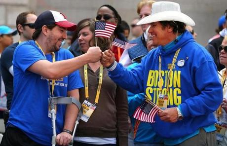 Double amputee Jeff Bauman (left), with aid-giver Carlos Arredondo, watched the finish.
