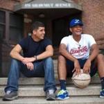 C.J. Nessralla (left) and Manny Peguero sat in front of the public housing unit that Manny lived in when they met.