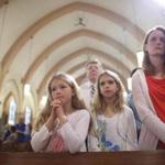 Monica Baker and daughters (from left) Leslie and Meredith take part in Mass at St. Mary Catholic Church in Franklin. 