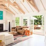 Owner and interior designer Jill Morelli spruced up the 1960s addition at the back of the house, opening up the ceiling to expose the pitched roof, painting the floor white, and adding French doors to the deck. 