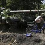 A resident of Novoazovsk, Ukraine, walked his bike passed a pro-Russia tank.  At least a half dozen tanks used by rebel fighters were seen on roads around town.