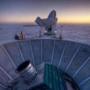 In this 2007 photo, the sun sets behind the BICEP2 telescope, foreground, and the South Pole Telescope in Antarctica. 
