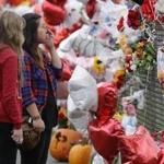 Francesca Tuazon (right) and Nicole Buell, both 17, visited a memorial on a fence Monday at Marysville-Pilchuck High School, where a student shot five classmates and then himself.