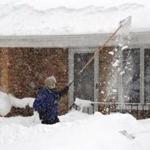 A man used a long fishing net to scrape snow off his roof just south of Buffalo, New York. 