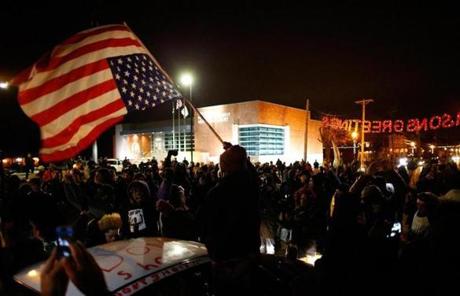 Protesters gather and wave a flag outside the police station in Ferguson.
