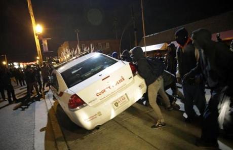 Protesters shoved a police car in Ferguson after the announcement of the grand jury decision not to indict Officer Darren Wilson.
