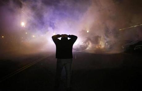 A protester stood with his hands on his head as a cloud of smoke approached in Ferguson, Mo.

