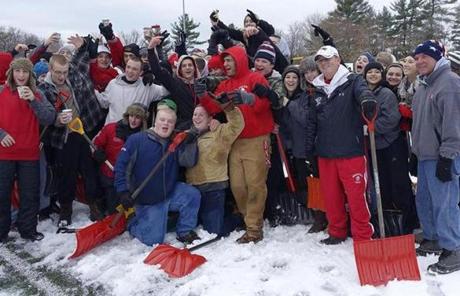 Wakefield head coach Mike Boyages (second from right) is joined by players, cheerleaders, and fans to assist in clearing the field.

