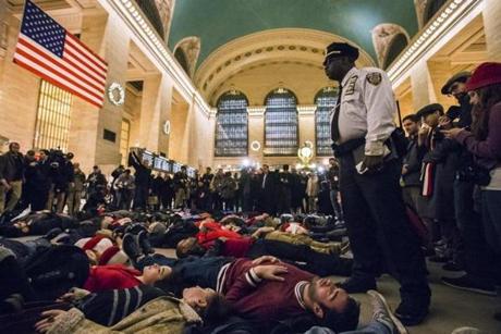 A police officer stood over activists who staged a 'die-in' during rush hour at Grand Central Terminal Wednesday. 
