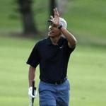 U.S. President Barack Obama waves to the crowd after chipping onto the 18th green as he finishes a round of golf.