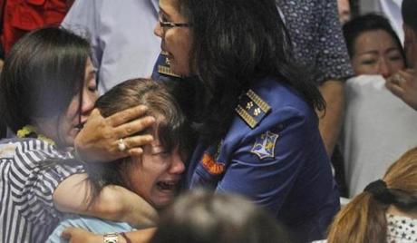 Relatives of passengers of the missing AirAsia Flight 8501 react upon seeing the news on television about the findings of bodies on the waters near the site where the jetliner disappeared.
