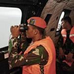 Indonesian air force personnel looked out of the windows of a helicopter as they searched for remnants of the doomed AirAsia Flight 8501, which was believed to have crashed into the Java Sea.