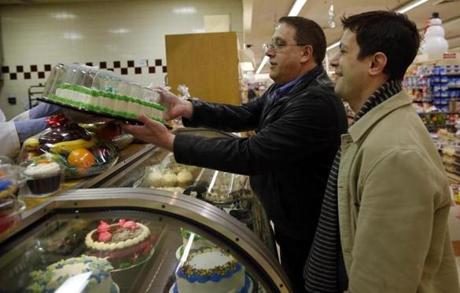 Tim Coco (left), and Genesio Oliveira, married since 2005, bought a cake at the Market Basket in Plaistow, N.H., to celebrate Oliveira?s long-awaited permanent residency.
