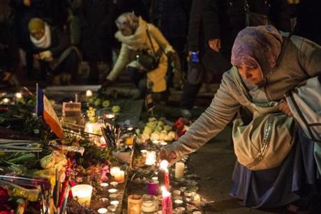 A Muslim woman lit a candle near the Charlie Hebdo offices, where 12 people were killed.
