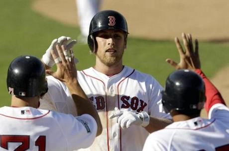 Boston Red Sox's Lars Anderson is greeted by teammates at home plate after hitting a grand slam during the seventh inning of a spring training baseball game against the Minnesota Twins, Sunday, March 4, 2012, in Fort Myers, Fla. (AP Photo/David Goldman)
