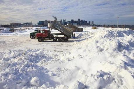 Dump trucks carrying snow that has been removed from roadways and sidewalks dump their payloads in a lot on South Boston. 
