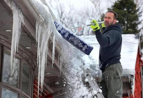 Tom McCann, owner of Clover Landscaping Co. of Weymouth, removed snow from a roof in Quincy with a roof rake.
