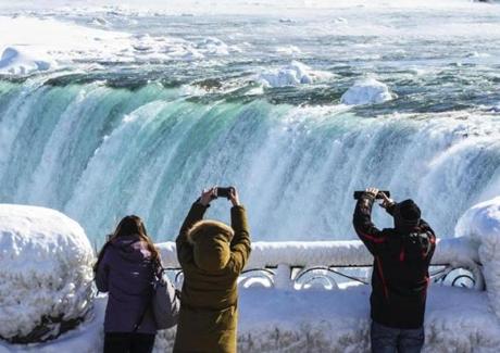 Sightseers took pictures of a nearly frozen Niagara Falls on Friday. 

