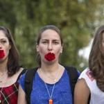 Protesters in Romania held carnations in their mouths during a 2011 protest against harassment of women initiated over their public appearance or behavior. 