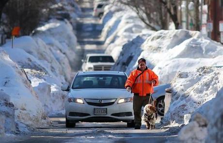 A man walked his dog down East Fifth Street in South Boston after a storm in February.
