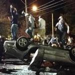 People stand atop an overturned car  during a night of violent parties last year during the annual Pumpkin Festival in Keene, N.H.