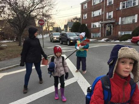 Nana Putt stops traffic so that Suleb and Anouk Noir and their mother, Talitha Reynolds, can cross the street on their way to the Coffin school in Marblehead. 

