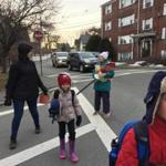 Nana Putt stops traffic so that Suleb and Anouk Noir and their mother, Talitha Reynolds, can cross the street on their way to the Coffin school in Marblehead. 
