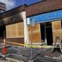 Workers boarded up storefronts damaged by the fire. 