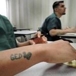 A GED tattoo motivates inmate Gerald Daughtry, Daniel Rexford (right) listens as Adam Frattasio explains mathematical concepts. 