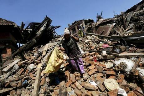 A woman carried her belongings as she walked over a collapsed house in Bhaktapur, Nepal.
