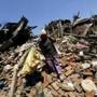 A woman carried her belongings as she walked over a collapsed house in Bhaktapur, Nepal.