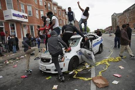 Protesters climbed atop a destroyed Baltimore Police car.
