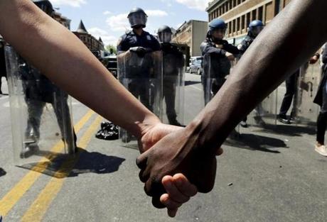Members of the community held hands in front of police officers in riot gear outside a recently looted and burned CVS store in Baltimore.
