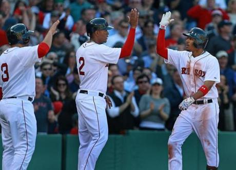 04/13/15: Boston, MA: The Red Sox Mookie Betts i(right) is greeted by teammates Sandy Leon (left) and Xander Bogaerts (center), who both scored ahead of him after he blasted a second inning three run home run to put Boston ahead 4-0. The Boston Red Sox hosted the Washington Nationals in their home Opening Day MLB baseball game at Fenway Park. (Globe Staff Photo/Jim Davis) section: sports topic: Red Sox-Nationals (1)
