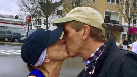 In this April 20, 2015 photo provided by Paige Tatge, her mother, Barbara Tatge, left, kisses an unknown spectator in Wellesley, Mass., as she ran in the Boston Marathon. It's a tradition for male runners to kiss the women attending Wellesley College as they line the marathon route. Barbara made good on a dare by her daughter, Paige, that she kiss a man as she ran along the route. Now they would like to know who she actually kissed. (Paige Tatge via AP)
